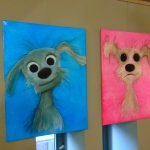 Ausstellung - Zwei kleine Comic Hunde. Einmal vor blauem Hintergrund und einmal vor pinkem Hintergrund