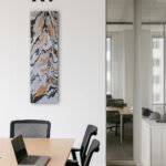 Vertikales abstraktes Gemälde mit Schwarz-, Weiß- und Orangetönen in modernem Konferenzraum mit Holz-Tisch und Glaswand